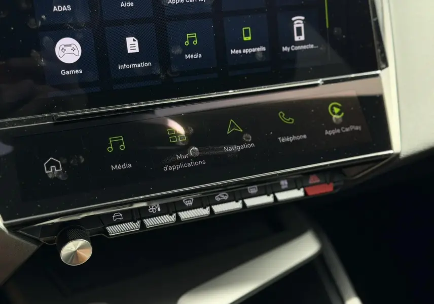 Vue rapprochée de la console centrale tactile de la Peugeot 308 Hybrid 2026, avec commandes multimédia et climatisation.