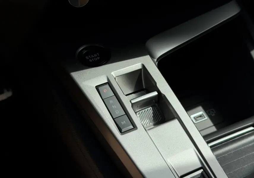 Gros plan sur la console centrale grise avec commandes de boîte auto et bouton start/stop du Peugeot 308 Hybrid blanc.