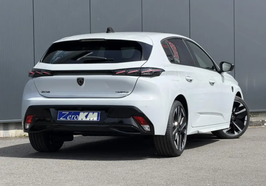 Vue 3/4 arrière droite d'une Peugeot 308 blanche Okenite avec jantes alliage bi-tons et feux arrière LED 3 griffes.