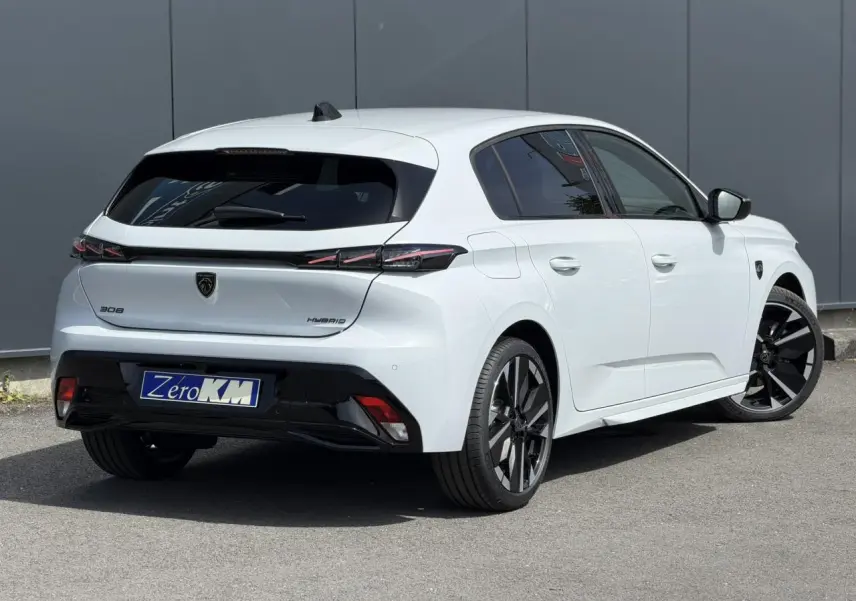 Vue 3/4 arrière droite d'une Peugeot 308 blanche Okenite avec jantes bi-tons et feux arrière à LED 3 griffes.