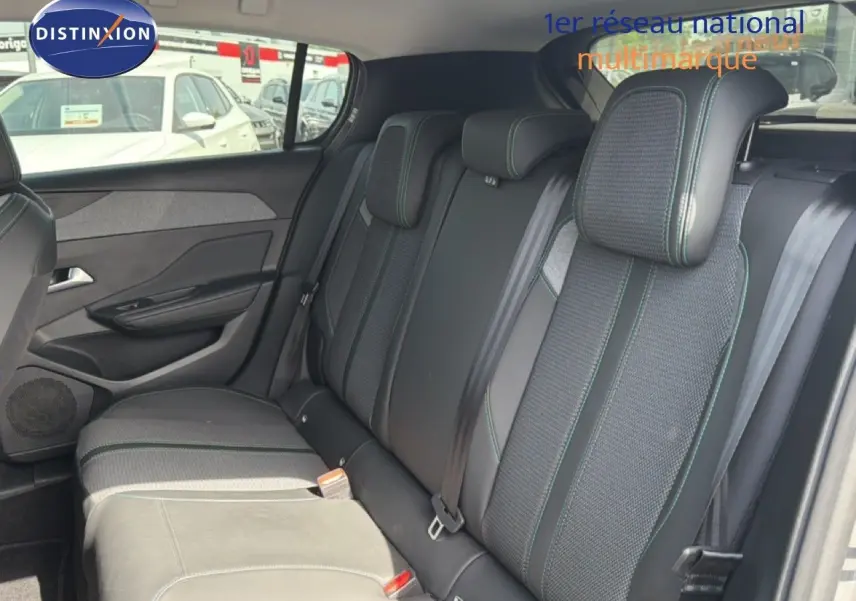 Vue intérieure arrière des sièges arrière en tissu noir avec surpiqûres vertes d'une Peugeot 308 Allure Hybrid 2025 gris Selenium Metal.