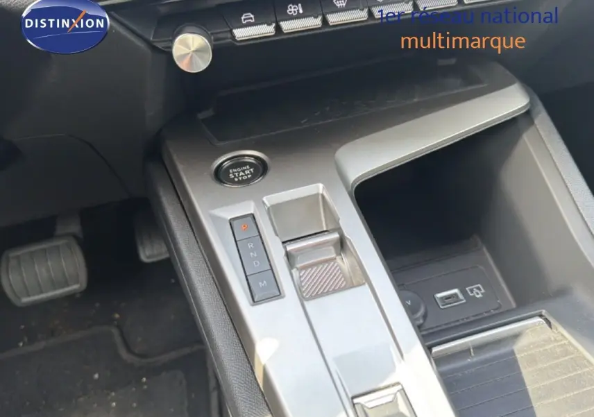 Vue rapprochée de la console centrale de la Peugeot 308 Allure Hybrid 2025, avec levier de vitesses automatique et bouton start/stop.