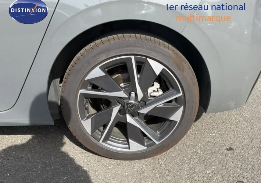 Gros plan sur la roue arrière droite d'une Peugeot 308 Allure Hybrid 145 gris selenium metal, jante alliage bicolore.