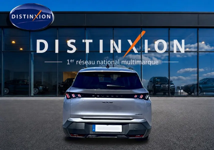 Vue arrière d’un Peugeot 5008 gris artense 2025 avec feux arrière LED et logo distinctif sur fond de vitrine Distinxion.