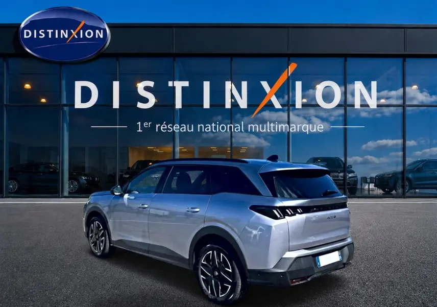 Peugeot 5008 Hybrid 145 allure e-dcs6 gris artense en 3/4 arrière droit devant un showroom Distinxion.