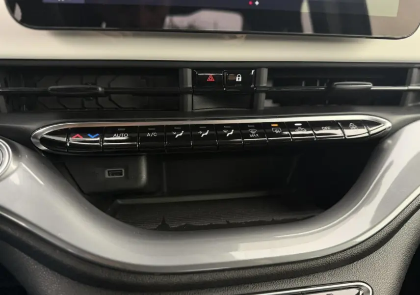 Vue rapprochée de la console centrale de la Fiat 500 électrique blanche, mettant en valeur les commandes de climatisation et ventilation.
