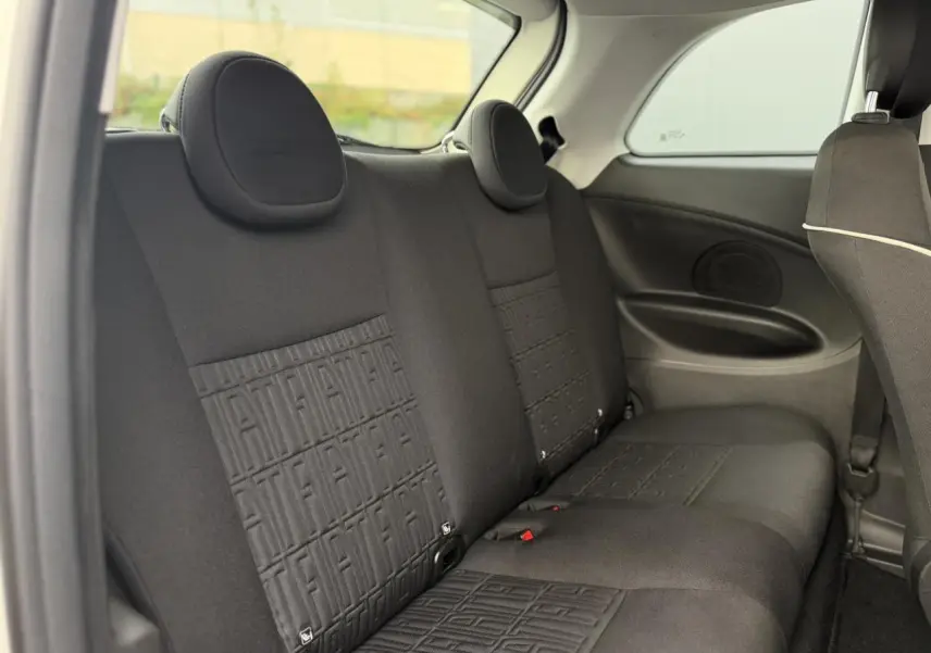 Vue intérieure des sièges arrière noirs de la FIAT 500 électrique 2024, avec motifs FIAT embossés sur les dossiers.