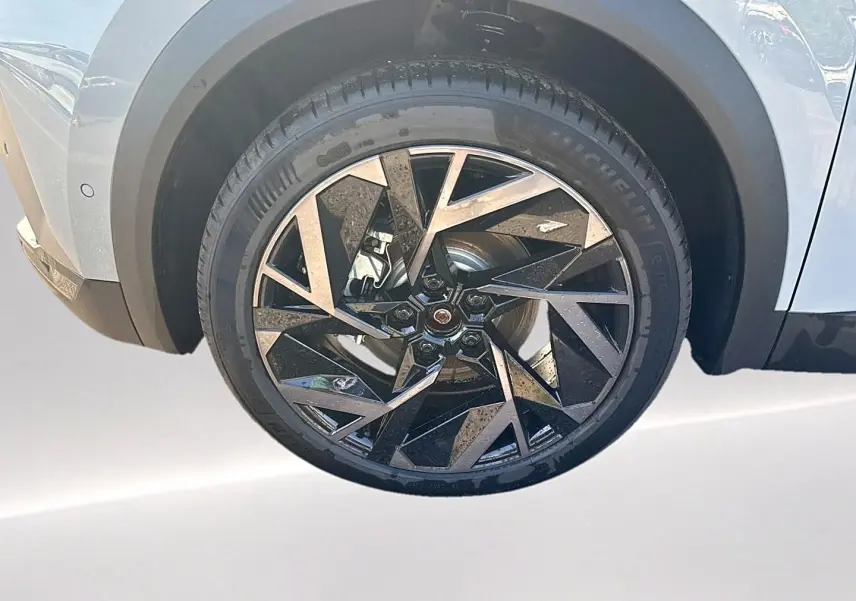 Gros plan sur la roue avant gauche du Renault Symbioz gris rafale, jante alu au design géométrique noir et argent.