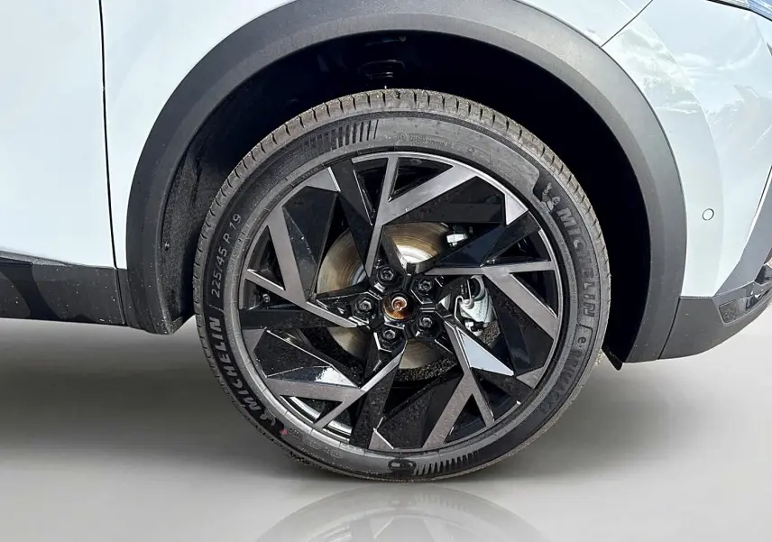 Gros plan sur la roue avant droite avec jante noire et grise du Renault Symbioz gris rafale, partie basse de la carrosserie visible.