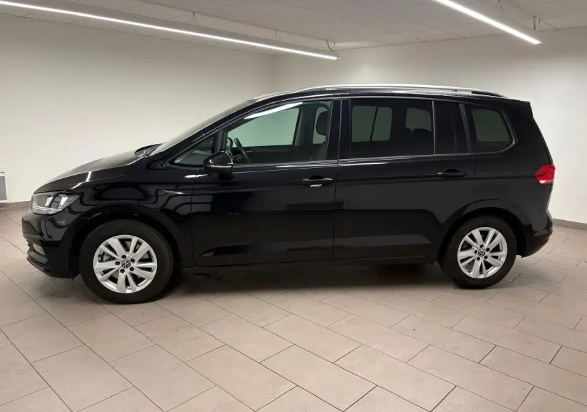 Profil côté gauche du Volkswagen Touran noir intense nacré 2024, monospace compact aux lignes épurées en intérieur neutre.
