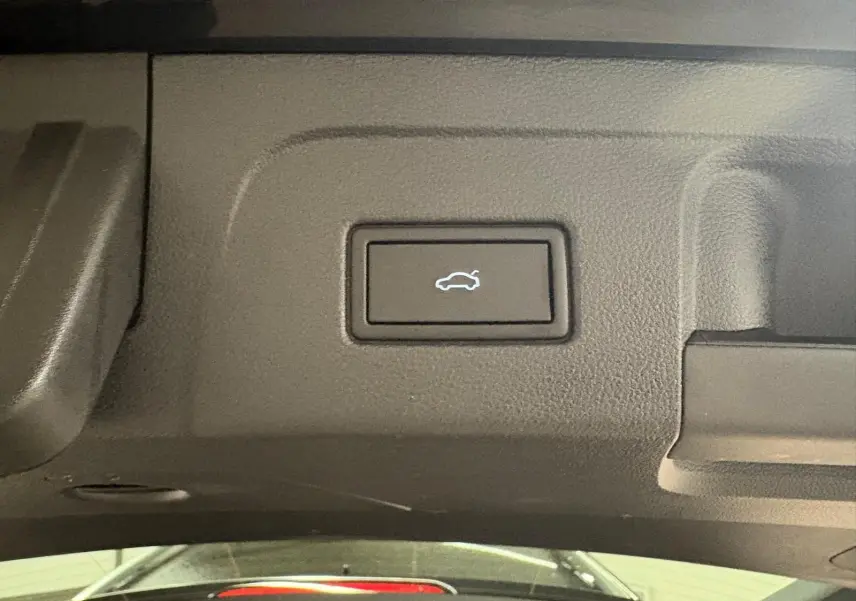 Bouton d'ouverture électrique du hayon sur le panneau intérieur du coffre du Volkswagen Touran noir intense nacré.