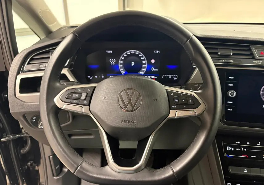 Vue rapprochée du volant cuir noir et du tableau de bord numérique du Volkswagen Touran 2024 Noir Intense nacré.