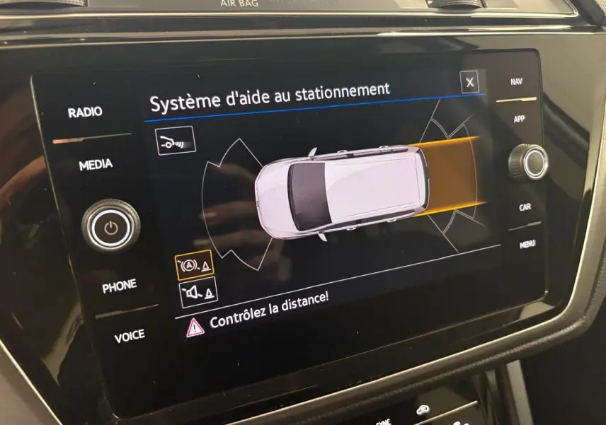 Écran tactile du système d'aide au stationnement dans l'habitacle du Volkswagen Touran noir intense nacré.