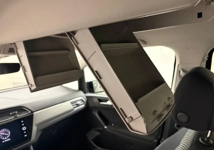 Vue intérieure du Volkswagen Touran 2024, coffre à lunettes ouvert au-dessus des sièges avant noirs.