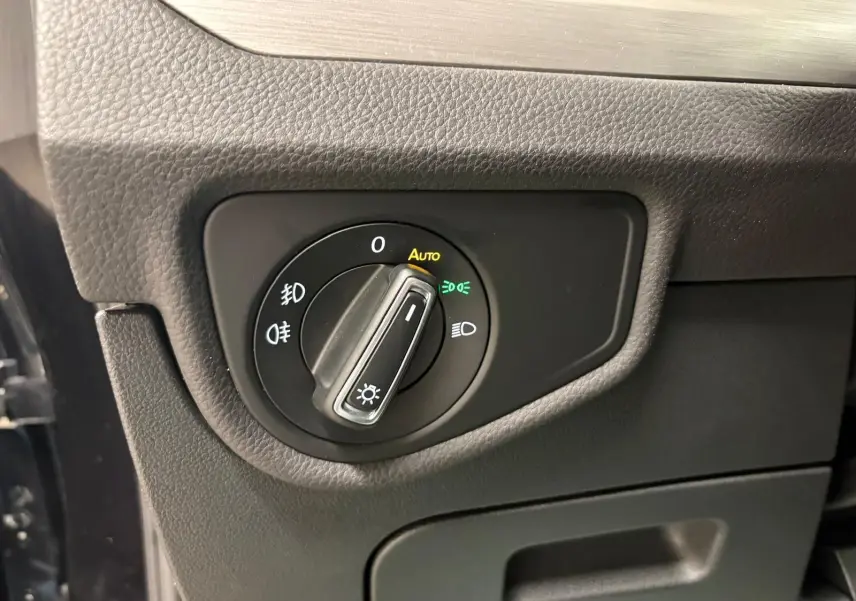 Gros plan sur le bouton de commande des phares du Volkswagen Touran noir intense nacré, intérieur côté conducteur.
