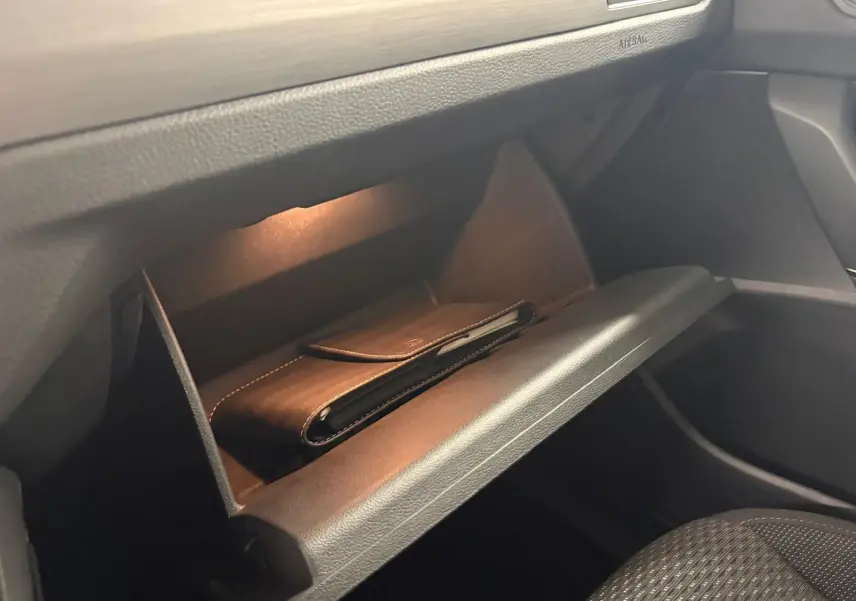 Gant de poche en cuir noir dans la boîte à gants éclairée côté passager du Volkswagen Touran 2024.