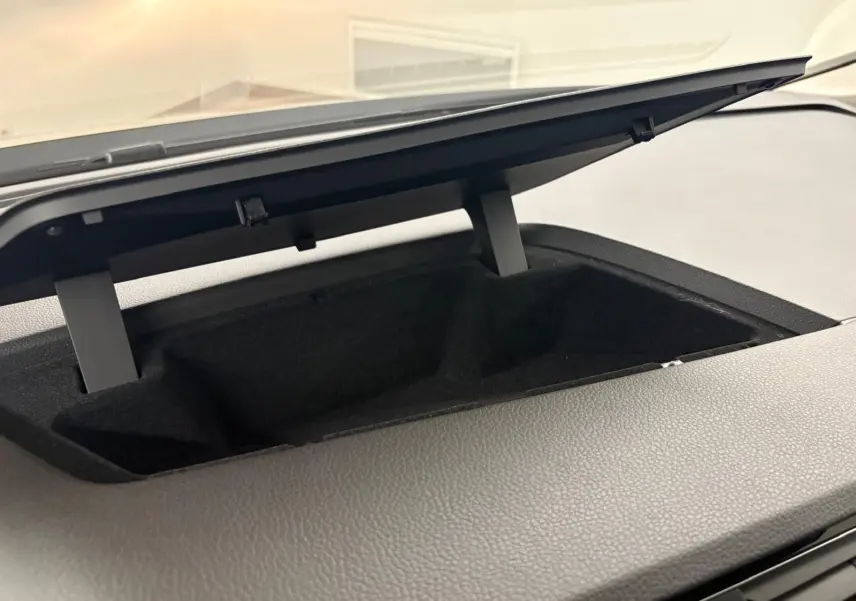 Rangement ouvert sur le tableau de bord du Volkswagen Touran 2024 noir intense nacré, vue intérieure rapprochée.