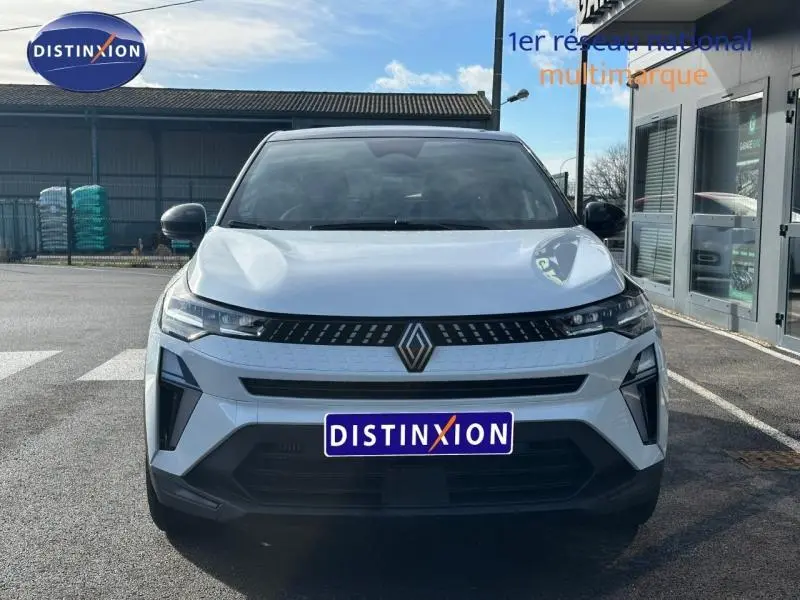 Vue avant d'un Renault Captur blanc nacré avec toit noir, calandre moderne et logo Renault central bien visible.