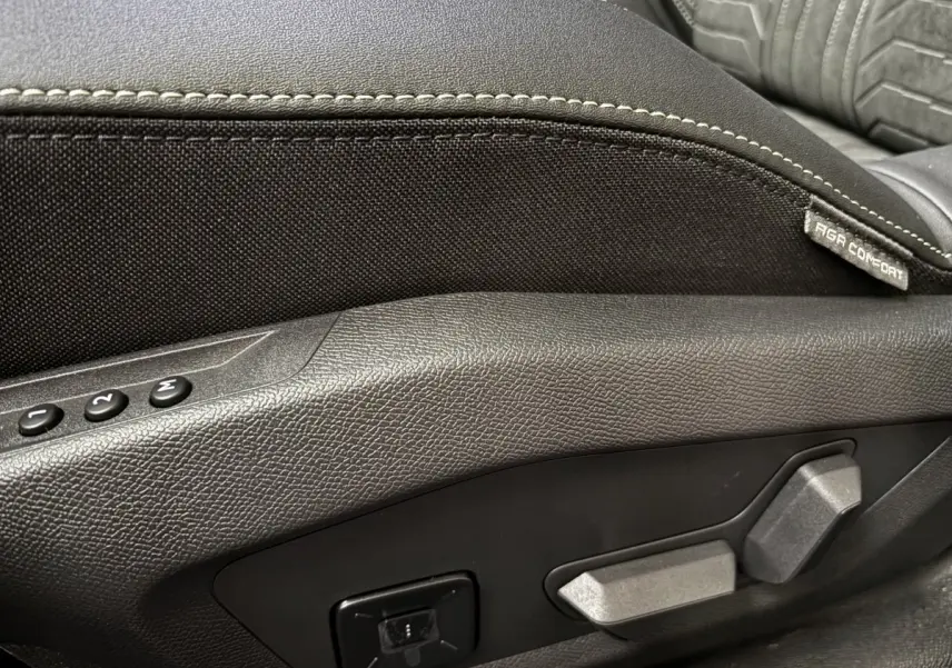 Détail des commandes de réglage électrique du siège avant noir du Peugeot 3008 hybride 2025.