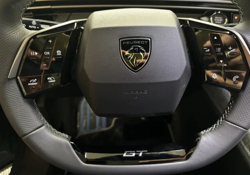 Vue rapprochée du volant cuir noir du Peugeot 3008 1.2 Hybrid 145 GT avec logo et commandes multifonctions.