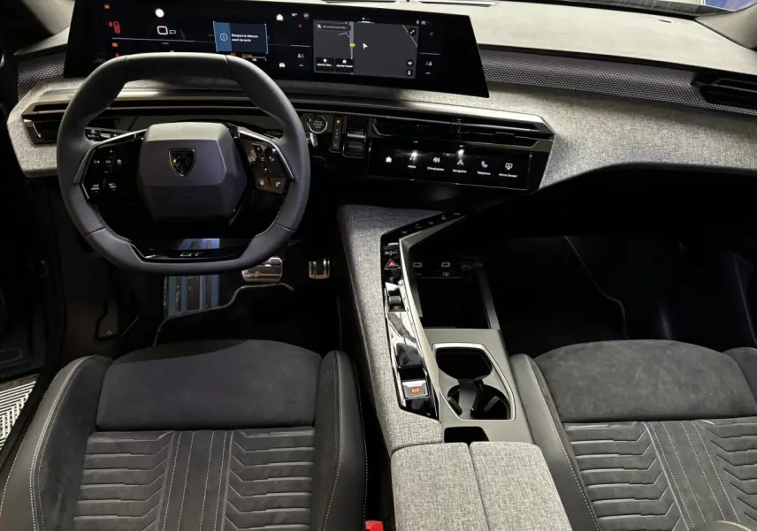 Vue intérieure avant du Peugeot 3008 1.2 Hybrid 145 GT, volant cuir GT, sièges tissu noir et console centrale grise.