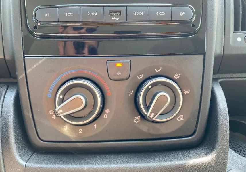 Gros plan sur la console centrale du Citroën Jumper 2023, avec commandes de climatisation manuelle et boutons multimédia.