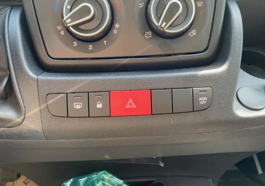 Gros plan sur la console centrale du Citroën Jumper 2023, montrant les commandes de climatisation et boutons de sécurité.