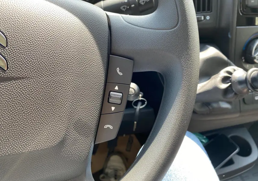 Gros plan sur le volant noir du Citroën Jumper 2023 avec commandes Bluetooth et levier de vitesse manuel visible.