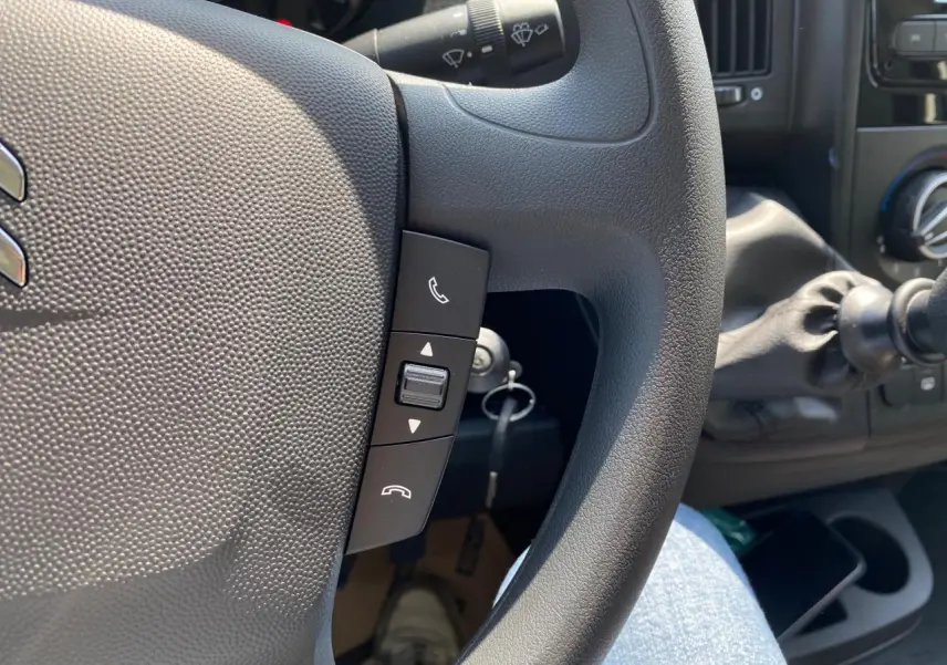 Gros plan sur le volant noir du Citroën Jumper 2023 avec commandes Bluetooth et levier de vitesse manuel visible.