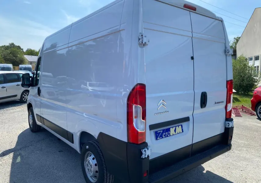 Vue 3/4 arrière droite d’un utilitaire Citroën Jumper blanc avec portes arrière tôlées ouvertes à 270°.