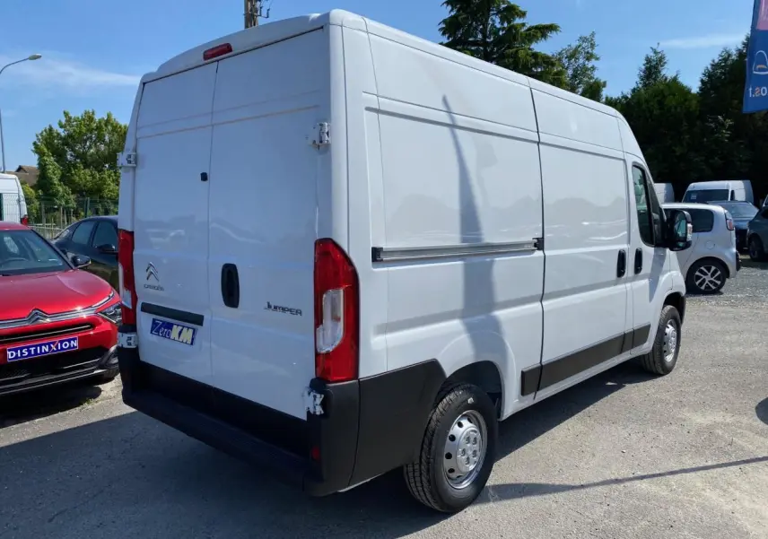 Vue 3/4 arrière droite d’un Citroën Jumper blanc 2023 avec portes arrière tôlées et jantes acier.