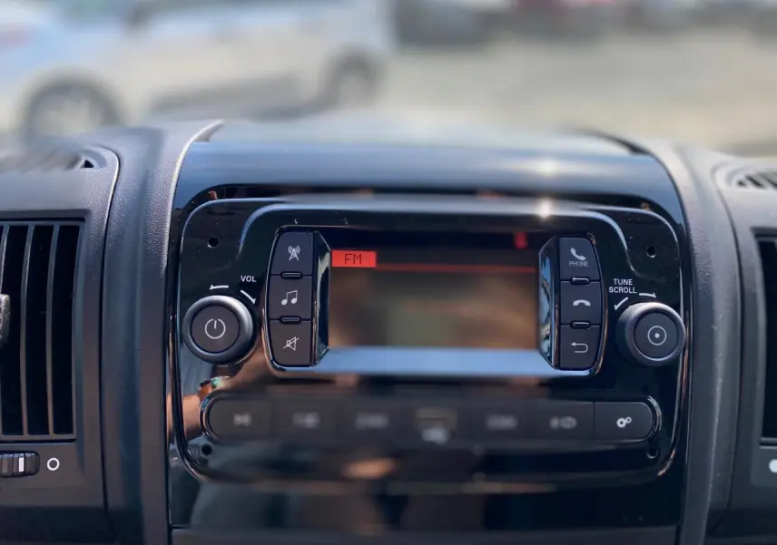 Tableau de bord du Citroën Jumper 2023 avec écran radio FM et commandes audio en gros plan.