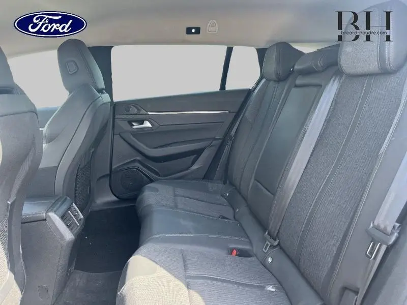 Vue intérieure montrant la banquette arrière en tissu gris avec appuis-tête et ceintures de sécurité du Peugeot 508 SW 2021.