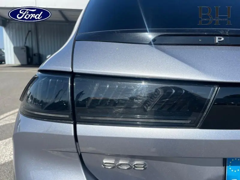 Gros plan sur le feu arrière gauche gris Artense d'une Peugeot 508 SW avec logo et badge visibles.