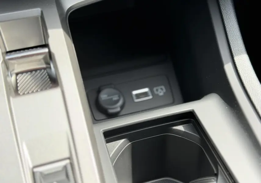 Gros plan sur la console centrale de la Peugeot 308 NV Hybrid 145 GT e-DSC6 noire, montrant prise 12V et port USB.
