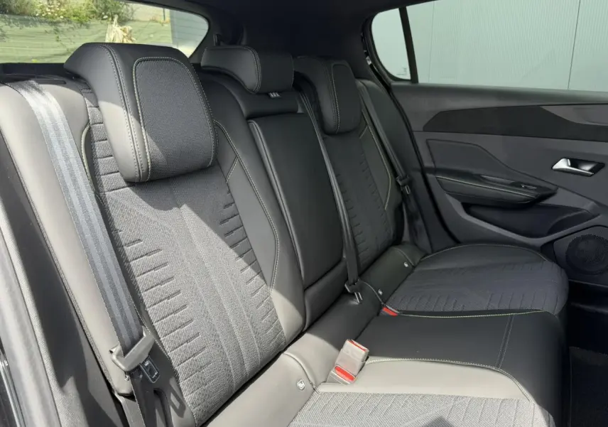 Vue intérieure côté droit des sièges arrière noirs avec surpiqûres vert Adamite de la Peugeot 308 NV Hybrid 2026.