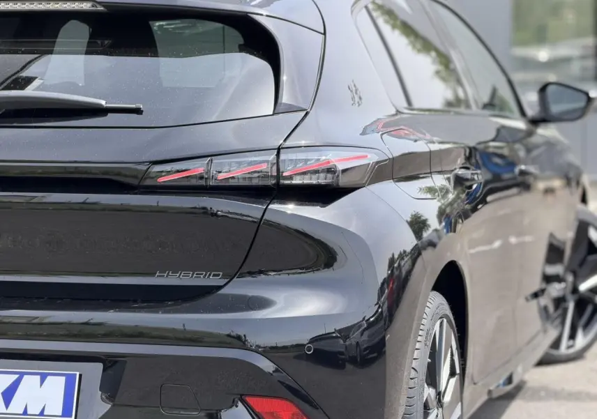 Vue 3/4 arrière droite de la Peugeot 308 NV Hybrid 145 GT e-DSC6 noir Perla avec feux arrière LED 3 griffes et jantes alliage bi-tons.