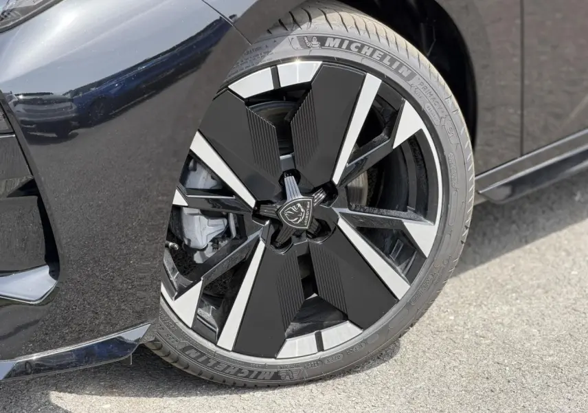 Gros plan sur la jante alliage 18" bi-tons noir et argent avec logo Peugeot, sur la roue avant droite noire Perla.