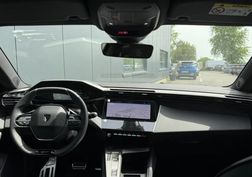 Vue intérieure avant du Peugeot 308 NV Hybrid 145 GT avec tableau de bord numérique et écran tactile central.