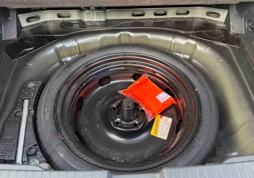 Gros plan sur la roue de secours noire dans le coffre d’un Volkswagen T-Roc 2025 avec trousse de sécurité rouge.