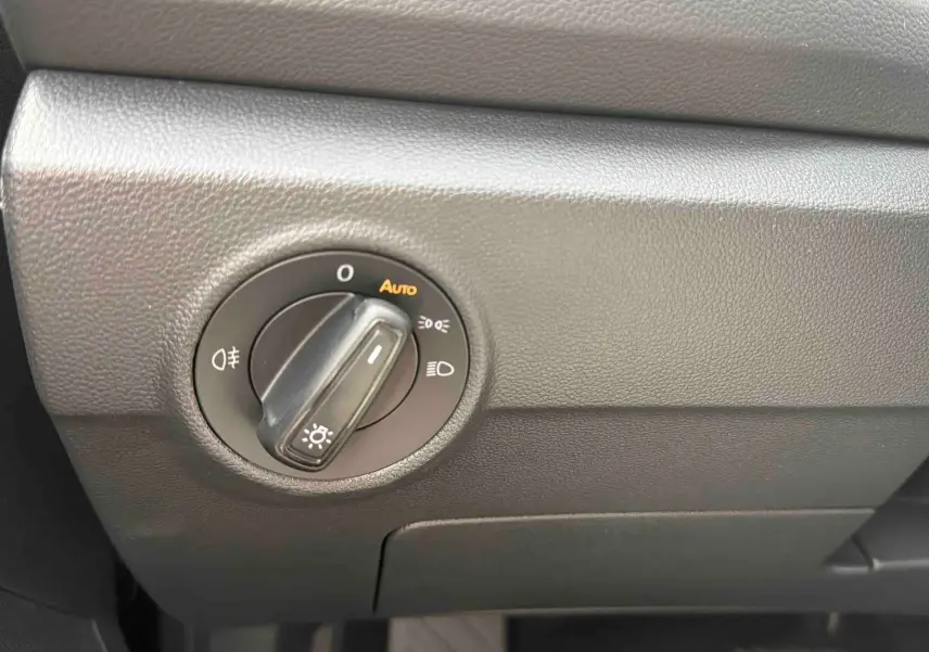 Gros plan sur le bouton de commande des phares du tableau de bord noir du Volkswagen T-Roc 2025.
