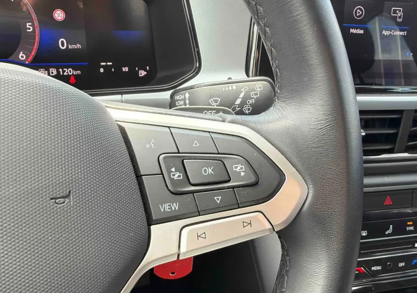 Gros plan sur le volant cuir multifonctions côté gauche du Volkswagen T-Roc noir avec tableau de bord digital et écran tactile.