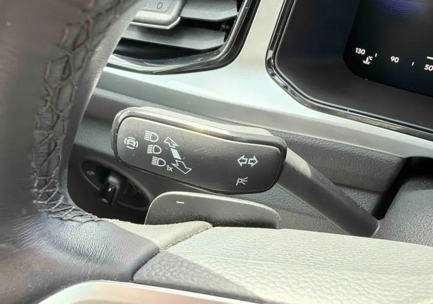 Gros plan sur la commande des clignotants et feux du Volkswagen T-Roc 2.0 TDI 150 DSG7, intérieur noir.