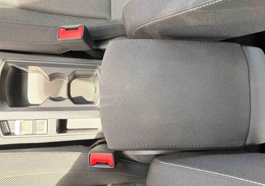 Vue plongeante sur la console centrale noire du Volkswagen T-Roc 2025, avec accoudoir et porte-gobelets.