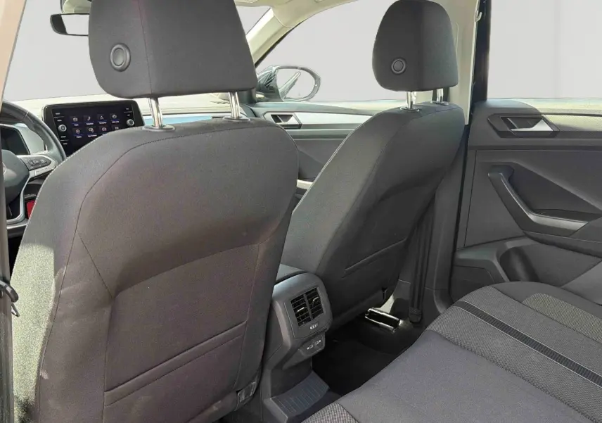 Vue intérieure arrière du Volkswagen T-Roc noir 2025, montrant les sièges avant, la console centrale avec aérateurs et port USB.
