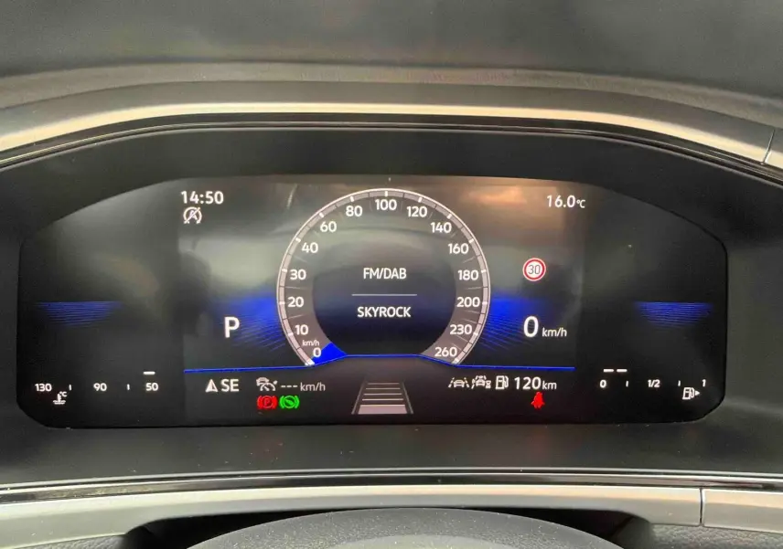 Vue rapprochée du combiné d'instruments digital du Volkswagen T-Roc noir, affichant la vitesse et la radio Skyrock.