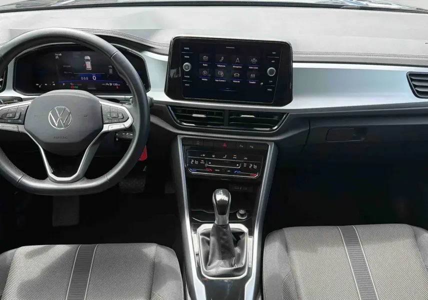 Vue intérieure avant du Volkswagen T-Roc 2025 noir, avec volant cuir multifonctions et écran tactile central.
