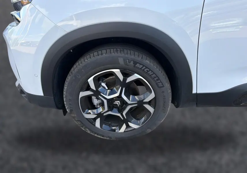 Gros plan sur la roue avant droite d’un Citroën C5 Aircross blanc avec jante alu bicolore distinctive.