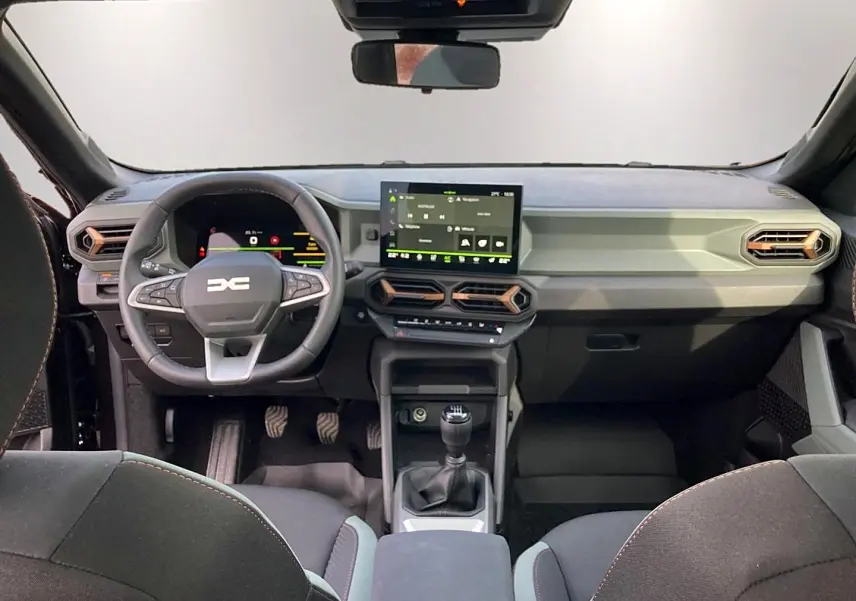 Vue intérieure avant du tableau de bord noir du Dacia Bigster 2025 avec volant multifonction et écran tactile central.