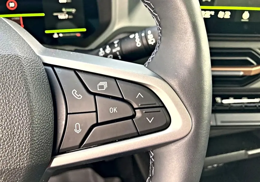 Gros plan sur les commandes multifonctions noires à gauche du volant du Dacia Bigster 2025, intérieur moderne.